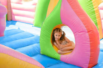 Baby girl in an colorful  inflatable castle attraction for entertaining funny jumping