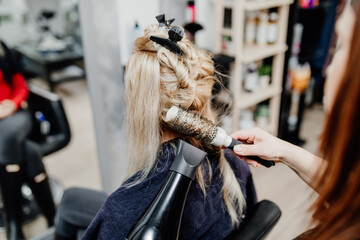 Beautiful hairstyle of middle-aged woman after dyeing hair and making highlights in hair salon.