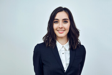 close up headshot portrait of a beautiful young adult businesswoman wearing black jacket on a white background studio