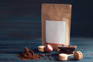 coffee  beans,  paper pack, macaroons and chocolate on wooden background