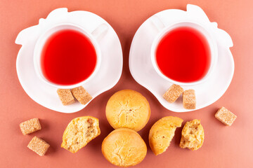 Two cups of raspberry tea and homemade rice cupcakes with raisins on a pink (coral) background. Rice flour muffins. Proper nutrition, gluten-free diet.