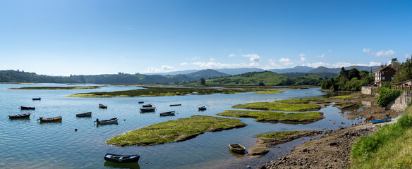 landscape of the San Vicente de la Barquera river delta and Picos de Europa in Cantabria with colorful wooden rowboats