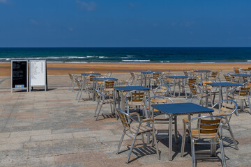 beachfront restaurant with empty chairs and tables and menu boards and no customers
