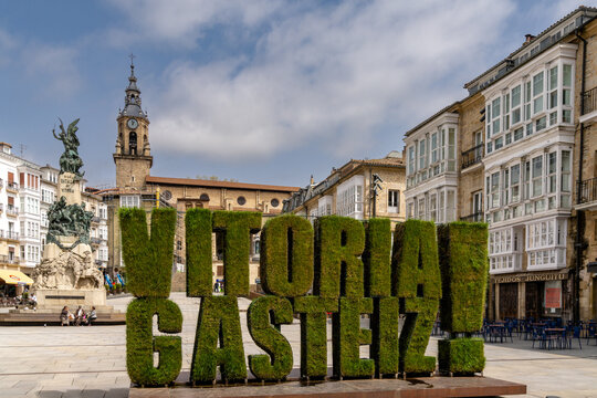 the Plaza de la Virgen Blanca square in the old city center of Vitoria with city name hedge in the foreground