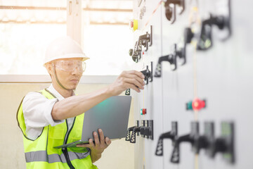 Electrical engineer or repairman holding laptop computer and looking at the screen to inspecting...