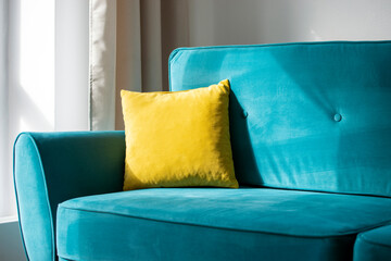 Bright yellow pillow on blue, turquoise sofa or couch, interior of the comfortable residential room - 504778986