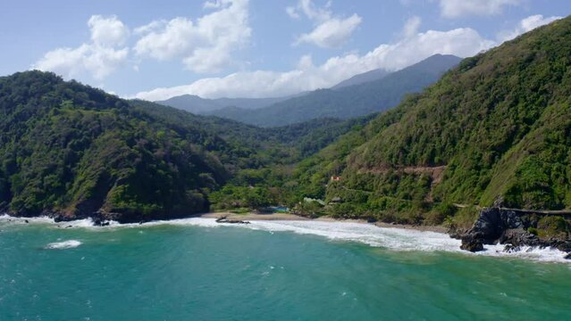 Aerial view Osma coastline. Waves crashing on the shore on a sunny day. Vargas State, Venezuela