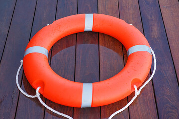 Red lifebuoy pool ring on the wooden floor of the swimming pool