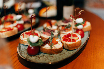 sandwiches with red caviar and red fish lie on the holiday table. The background is blurred. Microgreens