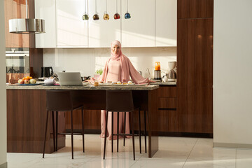 Muslim woman standing in kitchen with modern interior
