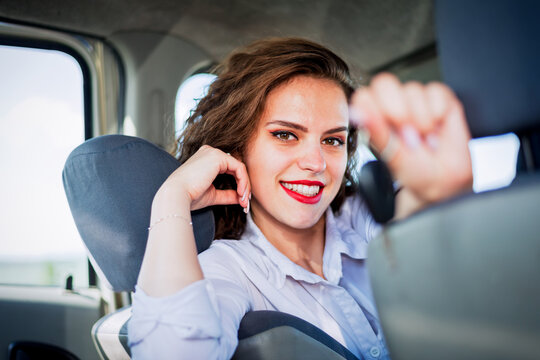 Beautiful woman driver showing car key and smiling while sitting inside her new car.Rental or buying auto concept.Auto insurance concept image.