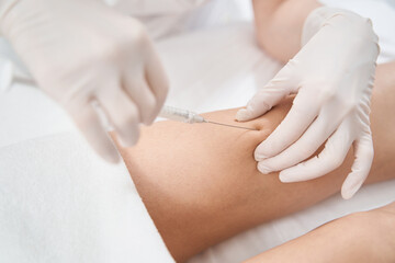 Woman receiving rejuvenation knee injection in clinic