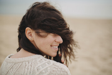 Beautiful happy woman with windy hair portrait on background of sandy beach and sea, carefree...