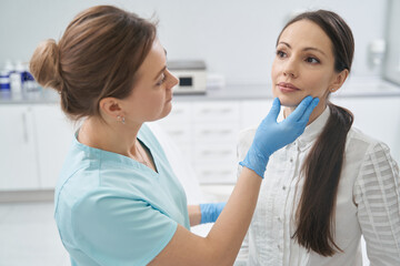 Doctor checking woman face skin in cosmetology clinic