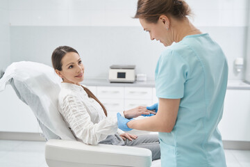 Fototapeta premium Doctor beautician checking woman hand skin in beauty salon