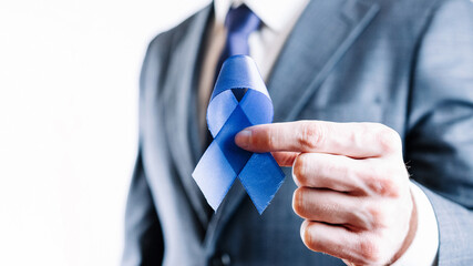 Cancer awareness blue. Business man with blue ribbon in hands on white background. Awareness prostate of men health. November and International Mens Day.