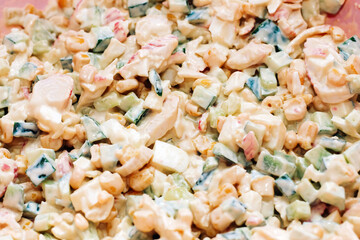 Salad with crab sticks, cubed cucumber, corn and egg with mayonnaise on a board.