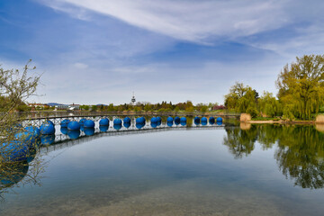 Floating bridge with blue round floats called 'Seeparkbrücke' at lake in Freiburg, Germany