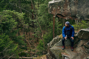 Fototapeta premium Backpacker sitting under rock with water bottle