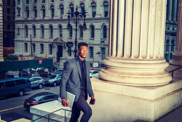 African American Businessman traveling, working in New York, wearing fashionable jacket, necktie, carrying laptop computer, walking into vintage office building from street.  filtered effect..