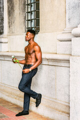 African American Man seeking love in New York. Shirtless, half naked, waring blue jeans, a young, strong, sexy guy standing by wall on street, holding white rose, thinking. filtered effect..