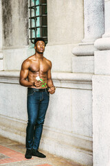 African American Man seeking love in New York. Shirtless, half naked, waring blue jeans, a young, strong, sexy guy standing by wall on street, holding white rose, thinking.  filtered effect..