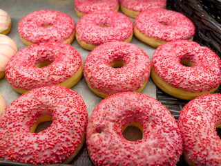 Assorted pink donuts in bakery shop