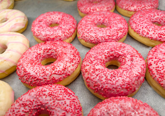 Assorted pink donuts in bakery shop