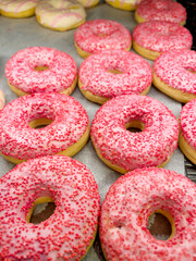 Assorted pink donuts in bakery shop