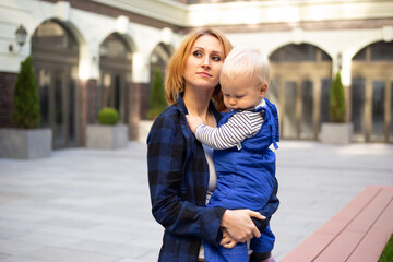 young woman portrait with child baby boy outdoors on urban background