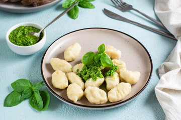 Potato gnocchi with pesto sauce on a plate on the table. Italian traditional cuisine. Close-up
