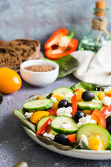 Greek salad of fresh vegetables, leaves and feta cheese on a plate. Vertical view. Close-up