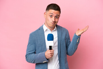 Young brazilian presenter man isolated on pink background having doubts while raising hands - obrazy, fototapety, plakaty