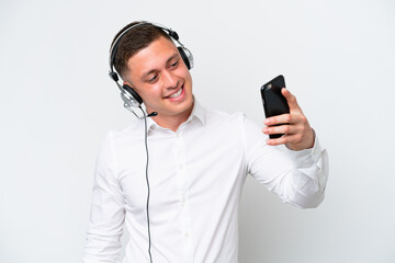 Telemarketer Brazilian man working with a headset isolated on white background making a selfie