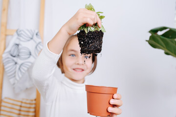 Amased little girl holding soiled plant roots assumed form of a pot