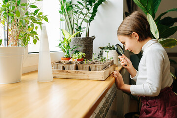 Side view of a girl looking at plant through a magnifying glass