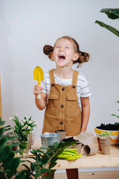 Spoiled little girl making a scene holding small shovel, next to plants, yelling