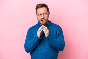 Middle age caucasian man isolated on pink background scheming something