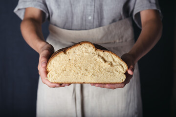 Female hands holding homemade fresh baked half bread. Gluten free, healthy diet concept. Dark rustic style.  