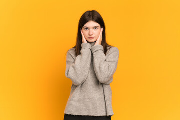 Young Ukrainian girl isolated on yellow background frustrated and covering ears