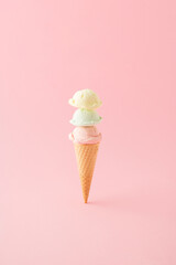 Ice cream with three scoops in a cone placed vertically on pink background. Minimal summer concept.