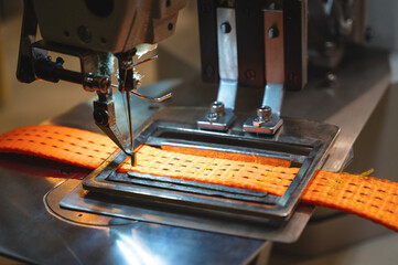 Sewing machine operates with orange towing strap in shop