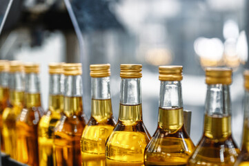 Bottles of golden alcohol with caps transported by conveyor