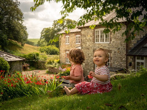 Little siblings girl and boy are eating fresh watermelon on a sunny day on her summer holidays at the countryside in a cottage in England