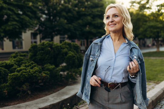 portrait of a successful senior woman in a blue shirt. Woman walks in the city