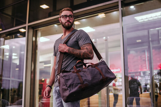 Millennial man in casual clothing and eyeglasses with a duffel bag