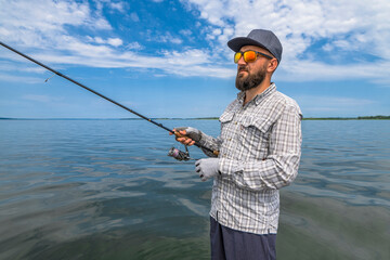 Spinning fishing. Bearded fisherman wait fish strike bite