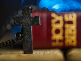Antique catholic cross, holy bible book on a wooden plain table on a blue background. Close-up. There are no people in the photo. Religion, Christianity, Catholicism, Faith, Forgiveness, Prayer