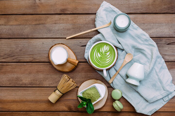 Green matcha tea in a white cup, tea powder and wooden spoon. Healthy drink. Top view, flat lay.