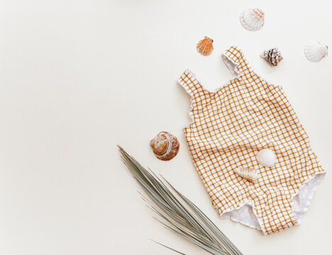 Summer concept for kids, cute retro baby swimsuit with wooden camera and palm leaf, holiday child background